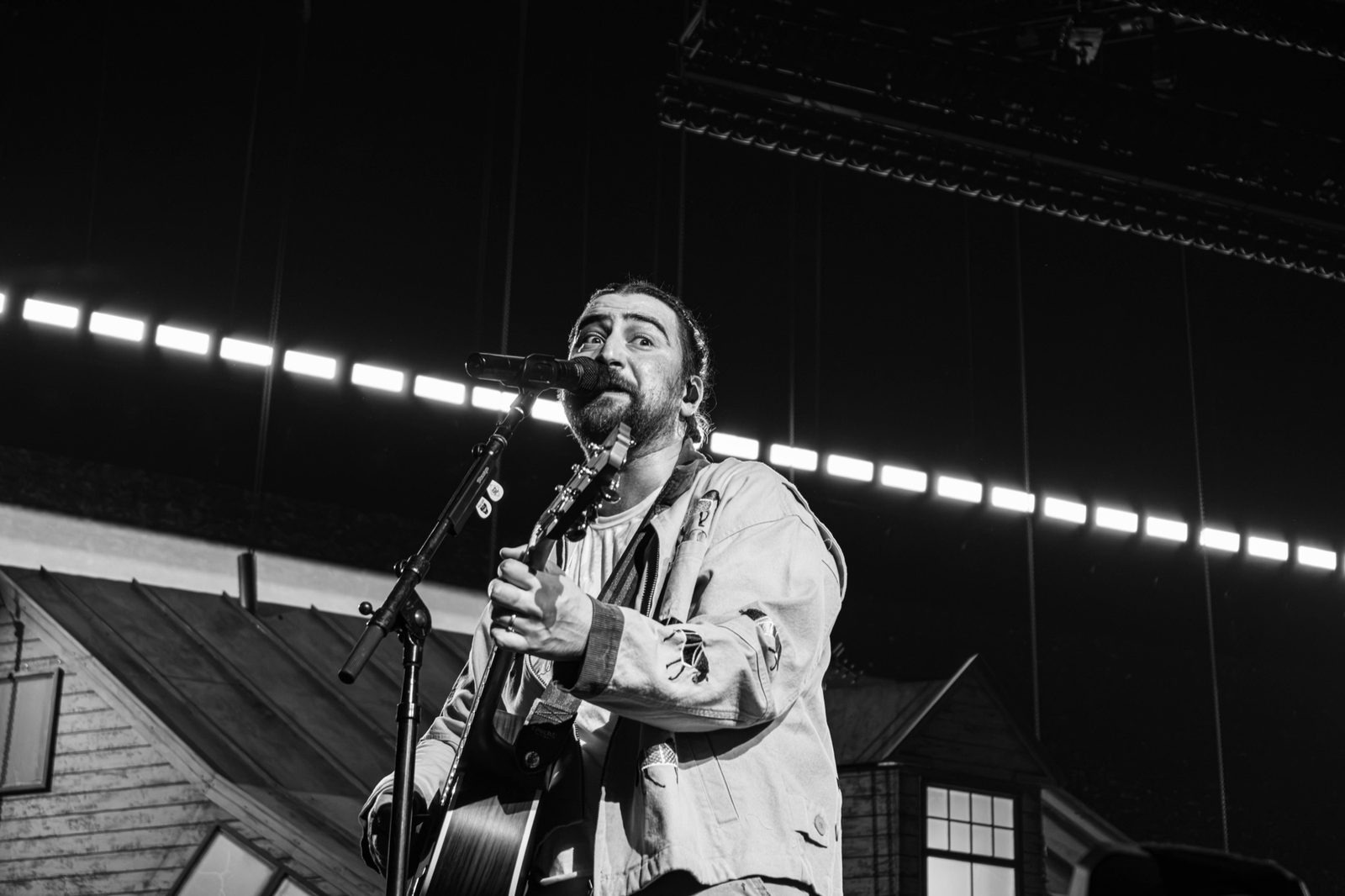 Black and white: singer at the mic with lighting rig behind