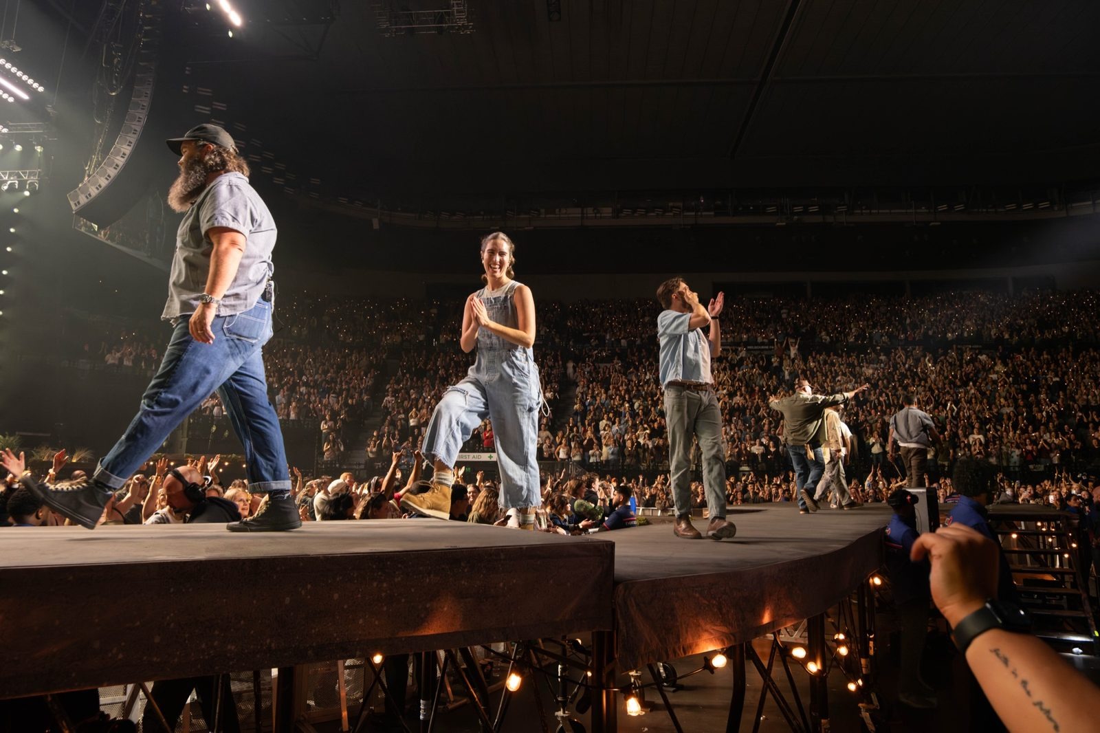 Band walking out along the stage runway into the arena