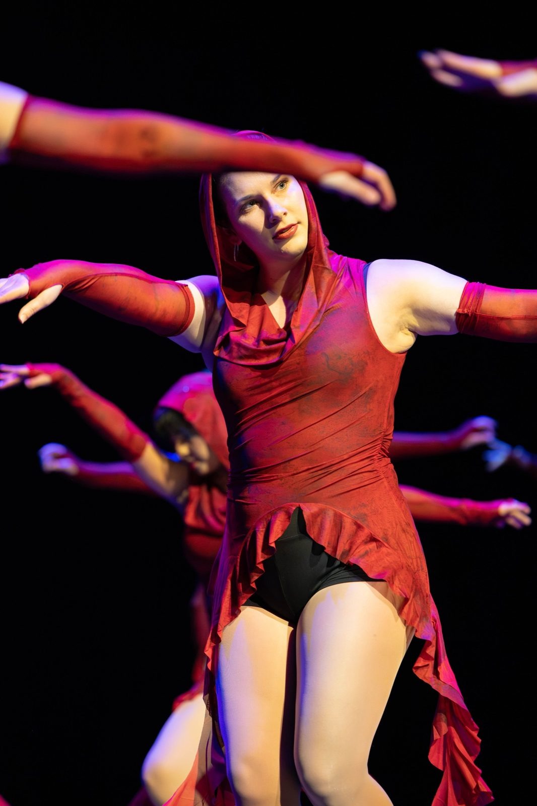 Dancer in a red fringed costume and long gloves, arms raised around her